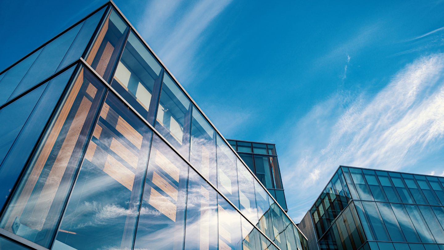 The glass facade of an office building against open sky